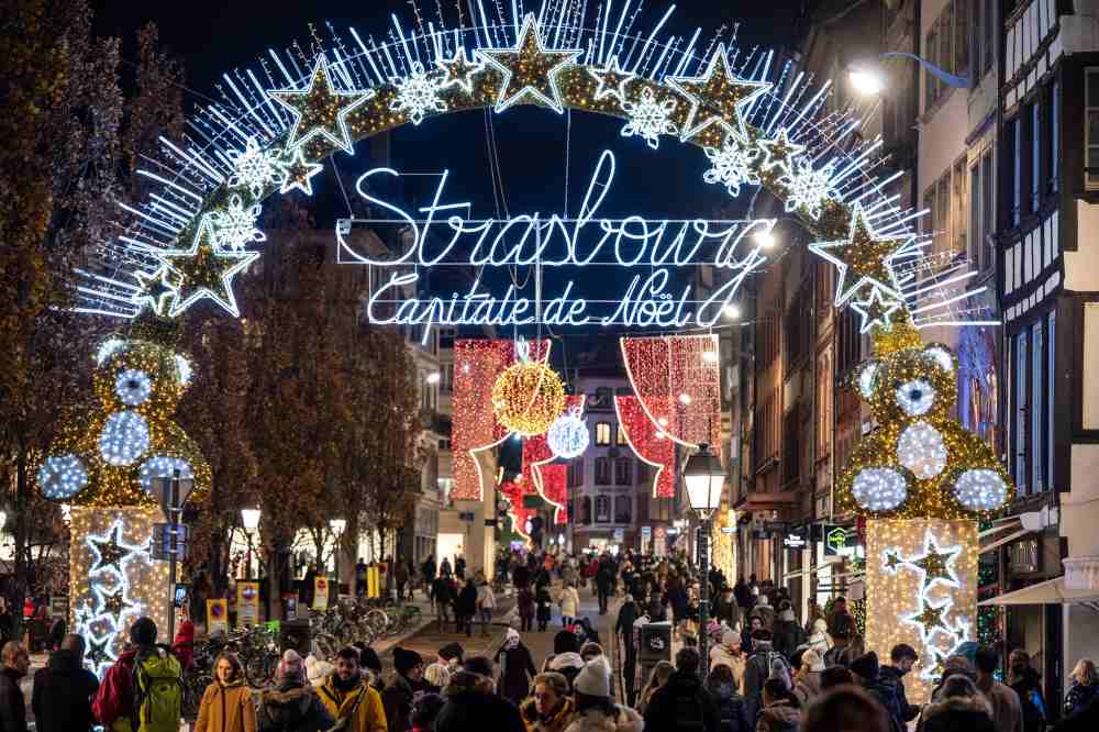 Arc entrance with lights and a lot of people passing by - best christmas markets in the world