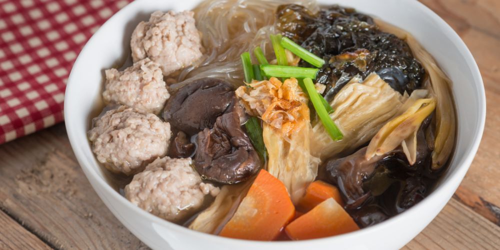 soup featuring glass noodles in a clear, mild broth loaded with minced pork, vegetables, and tofu.
