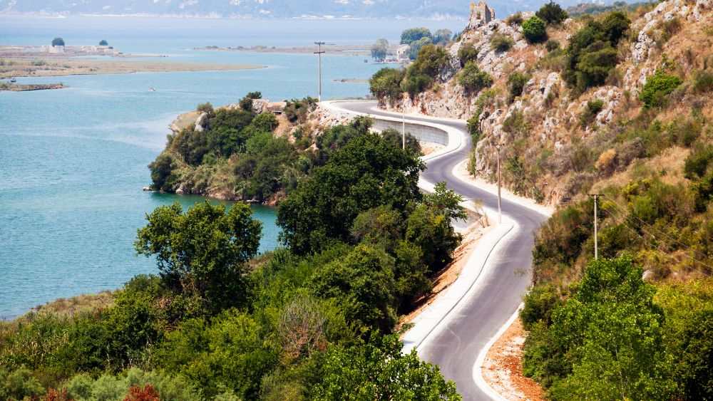 aerial view of a curvy road near body of water