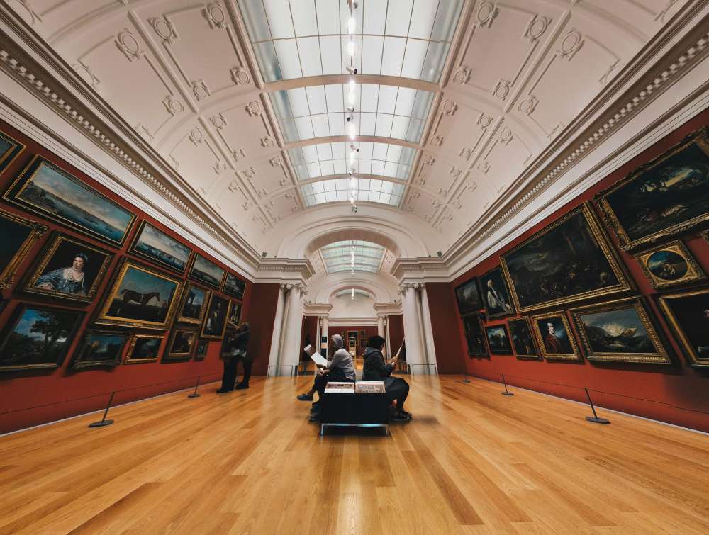 People sitting and reading in the middle chair inside museum