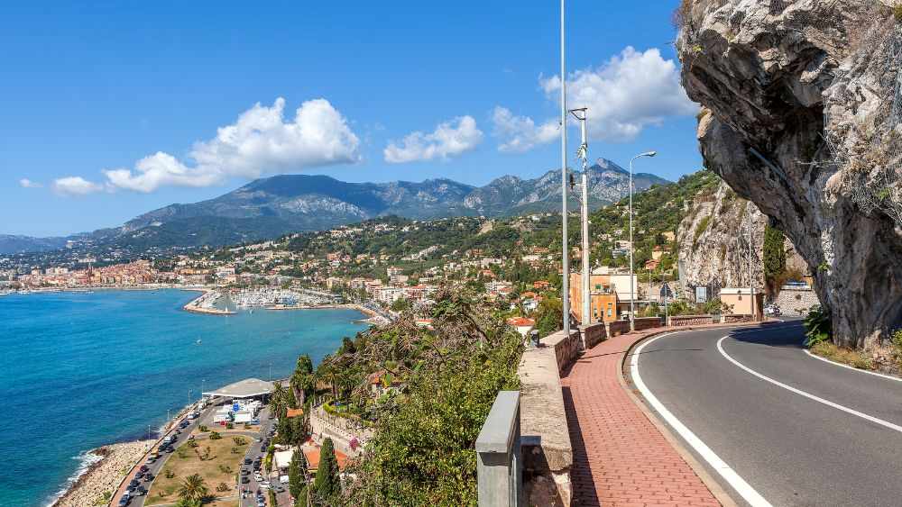 empty road with big rock in the side and other side showing Mediterranean Coast