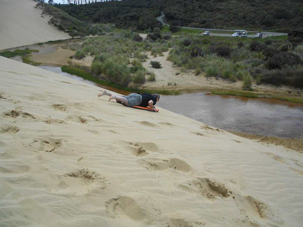 a man Sandboarding at Te Paki Sand Dunes