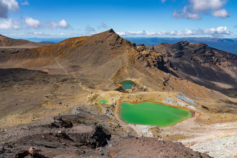 volcanic landscape marked by emerald lakes rugged peaks and steaming vents